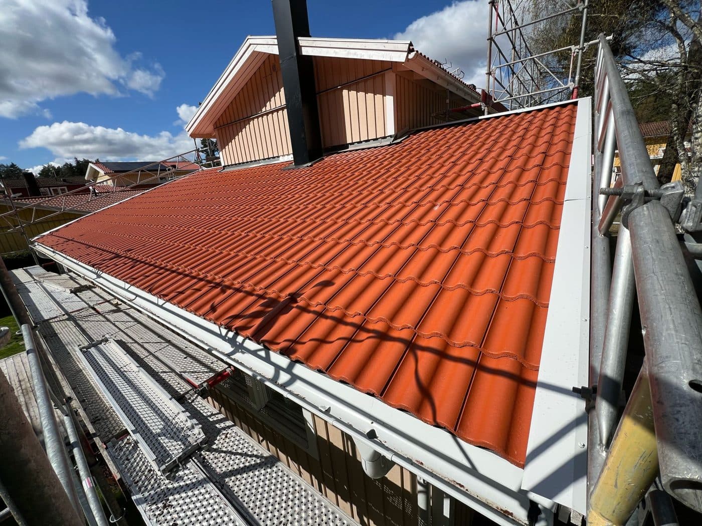 Nytt rött tegeltak mot blå himmel